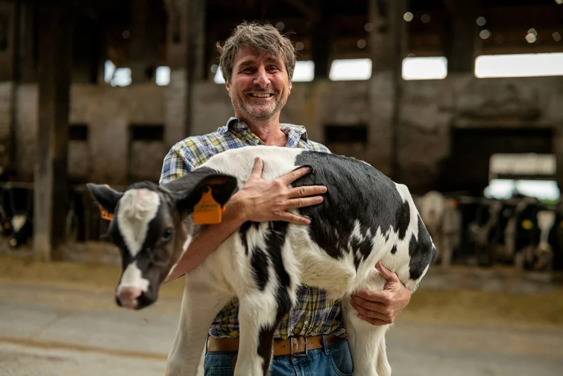 farmer proudly holding up a baby cow